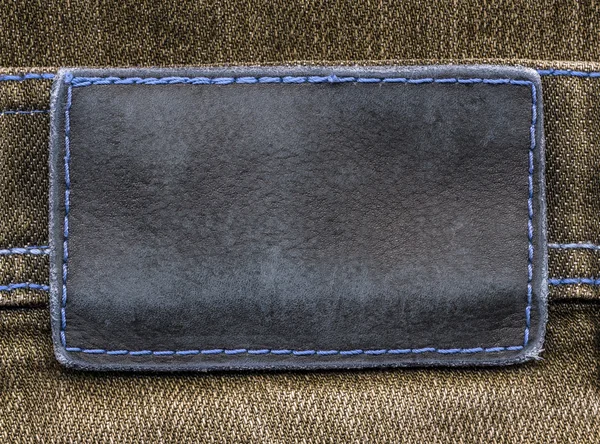 Etiqueta de cuero gris-azul sobre fondo vaquero marrón — Foto de Stock