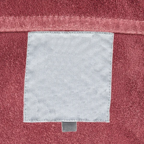 Etichetta tessile bianca su sfondo di pelle naturale — Foto Stock