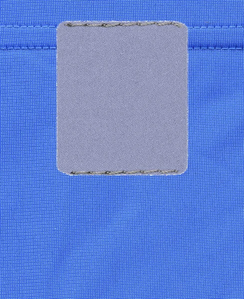 Šedé prázdný popisek na pozadí modré textilní — Stock fotografie