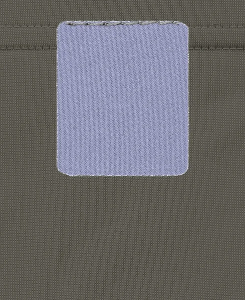 Cinza-azul etiqueta têxtil em branco sobre fundo têxtil — Fotografia de Stock