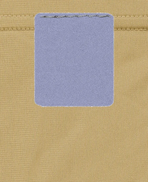 Cinza-azul etiqueta têxtil em branco no fundo têxtil amarelo — Fotografia de Stock