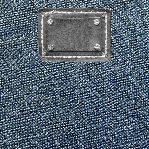 Textura azul denim, etiqueta de couro preto em branco — Fotografia de Stock