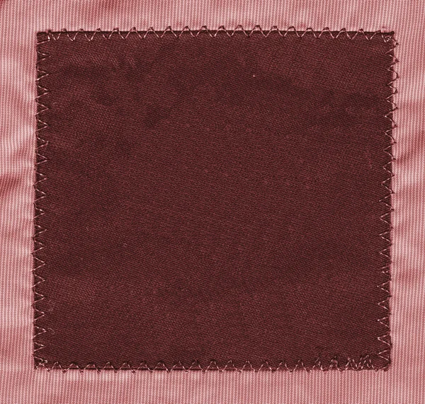 Red textile tag on reddish textile background — Stock Photo, Image