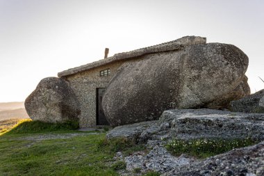 Serra de Fafe, Portekiz. Dört dev granit kaya arasında inşa edilen Casa do Penedo Kuzey Portekiz 'in ortasında gün batımında altın renginde parlar.