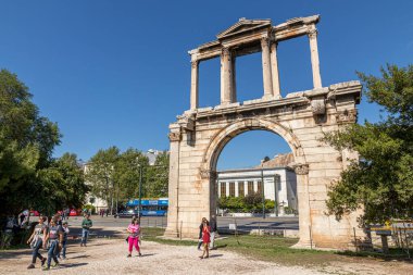 Atina, Yunanistan. Hadrian Kemeri 'nin geniş açı görüntüsü, açık mavi gökyüzünün altından geçen turistler, antik güzergah boyunca uzanan 2. yüzyıldan kalma Roma anıtını gösteriyor.
