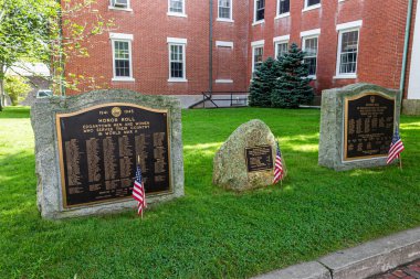Edgartown, Massachusetts. İkinci Dünya Savaşı 'ndan kalma üç taş savaş anıtı ve metal plaketli Vietnam gazileri için, küçük Amerikan bayrakları monolitlerden önce çimlere yerleştirilmiş.