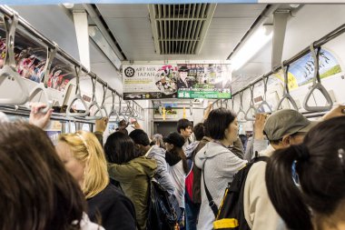 Tokyo, Japonya. Kalabalık bir metro vagonunun içi. Başkentteki trenlerin tipik el kemerleri ve tavan reklamlarıyla dolu.