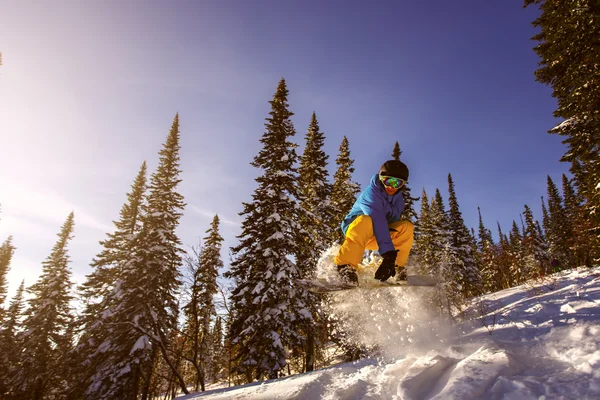 Saltando snowboarder em snowboard em montanhas — Fotografia de Stock