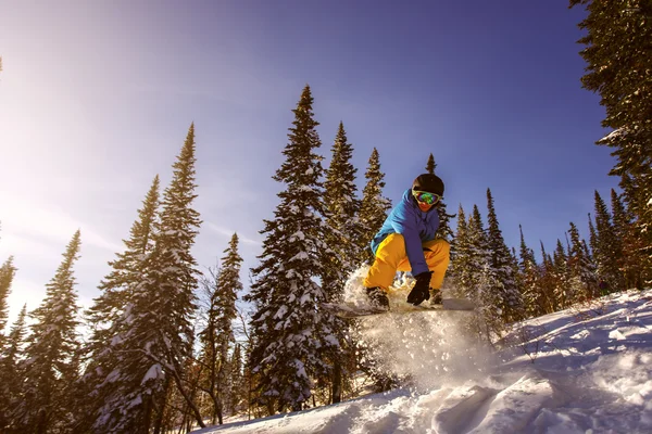 Saut snowboarder en snowboard en montagne — Photo