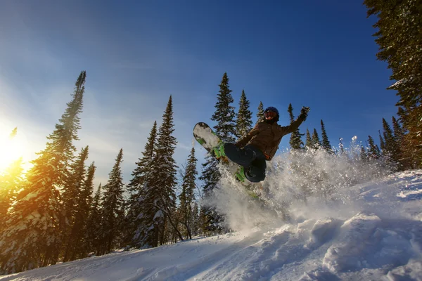 Hoppande snowboardåkare på snowboard i bergen — Stockfoto