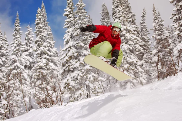 Salto snowboarder su snowboard in montagna nella stazione sciistica — Foto Stock