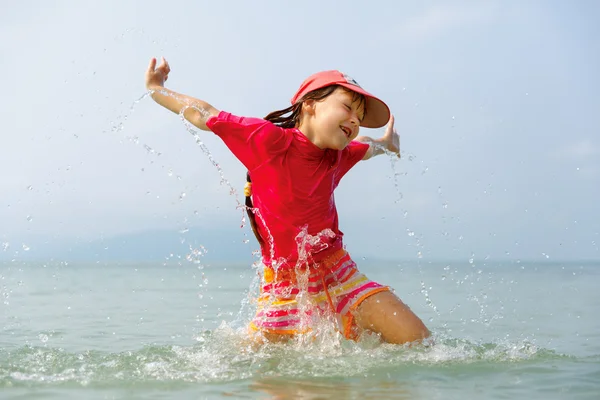 Little girl laughing and crying in the spray of waves at sea — Stock Photo, Image