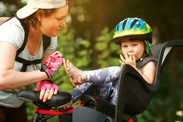 Ung kvinna på en cykel med lilla dotter — Stockfoto