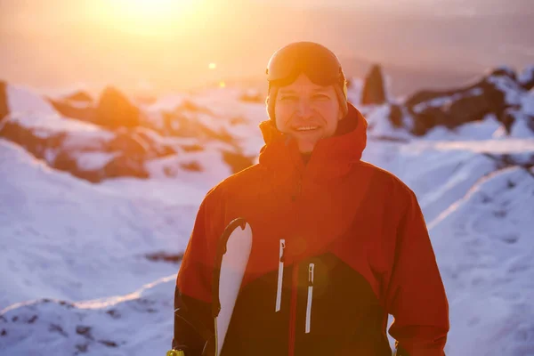 Mladý Snowboardista Usměje Drží Rukou Snowboard Ním Zapadající Slunce Royalty Free Stock Fotografie
