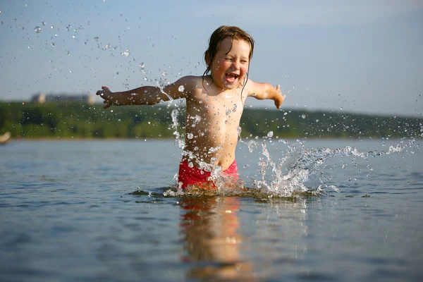 Little girl laughing and crying in the spray of waves at sea