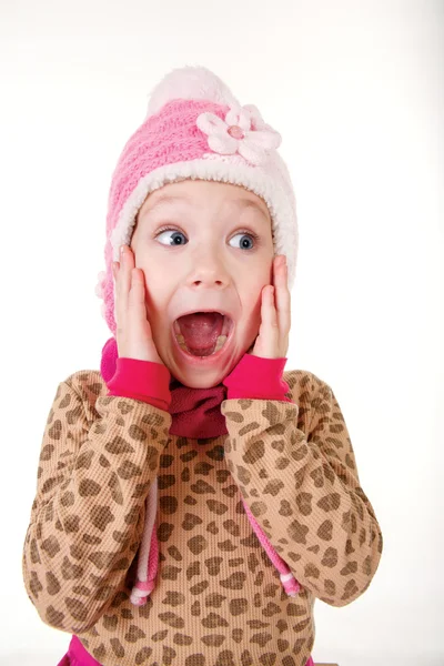 Cute little girl in red hat holding hands to face in surprise — Stock Photo, Image