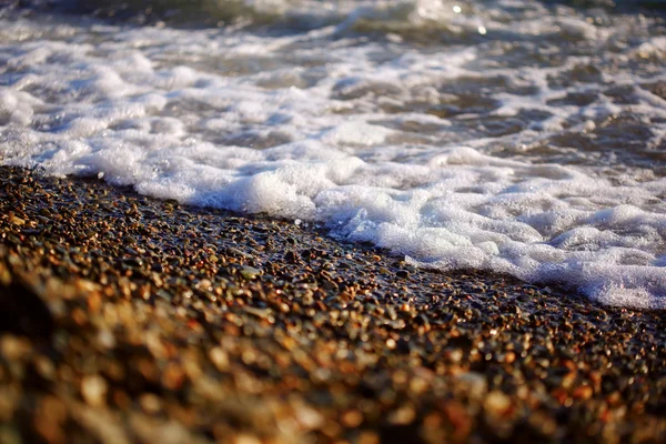 波と夕日海岸の小石 — ストック写真