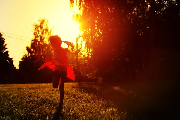 夕日で踊る赤いドレスを着た少女 — ストック写真
