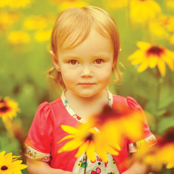 Belle petite fille heureuse assise sur une prairie verte avec des fleurs jaunes pissenlits sur la nature dans le parc — Photo