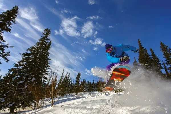 Snowboarder jumping through air with deep blue sky — Stock Photo, Image
