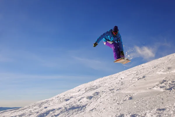 Snowboarder jumping through air with deep blue sky — Stock Photo, Image