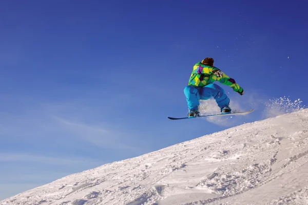 Сноубордист стрибає через повітря з глибоким блакитним небом — стокове фото