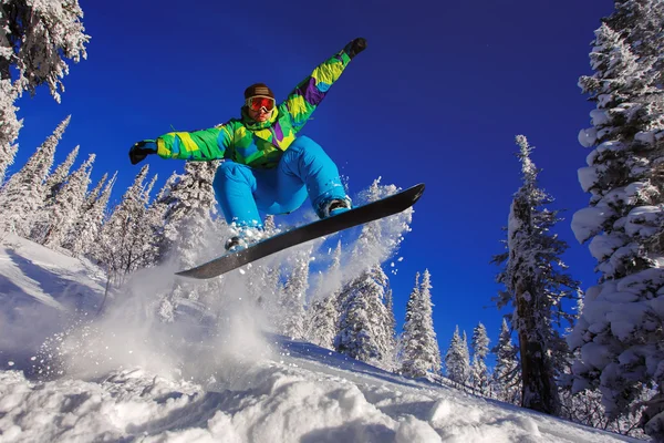 Snowboarder springen door de lucht met diep blauwe lucht op de achtergrond — Stockfoto