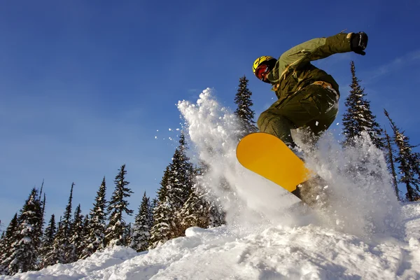 Snowboarder hoppar genom luften med djupblå himmel i bakgrunden — Stockfoto