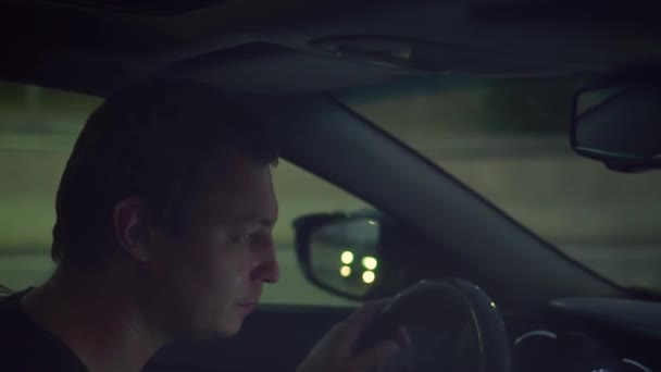 Férfi egy lerobbant autóban áll vészjelzésekkel a pályán este — Stock videók