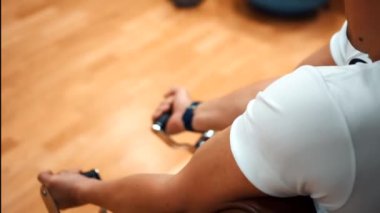 Spor salonundaki adam kollarını çalıştırıyor.