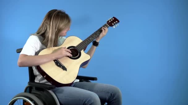 Девушка-инвалид в инвалидном кресле учится играть на гитаре — стоковое видео