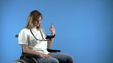 Tekerlekli sandalyedeki engelli bir kız telefona bakar.