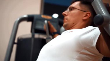 Spor salonundaki adam kollarını çalıştırıyor.