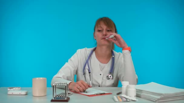 Joven médico novato llena el papeleo y fuma — Vídeos de Stock