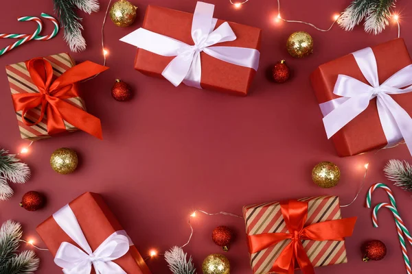 Kırmızı arka plan, hediyeler, süslemeler, Noel çelenkleri ve baston şekerler. Mesaj için yer. Xmas, köknar dallarıyla yatıyordu. Ortadaki boşlukta. Kimse..