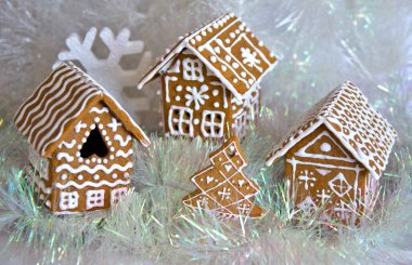 Noel kurabiyesi evleri ve yeni yıl ağacı şeklinde bir kurabiye. Arka planda gümüş süslemeler var.