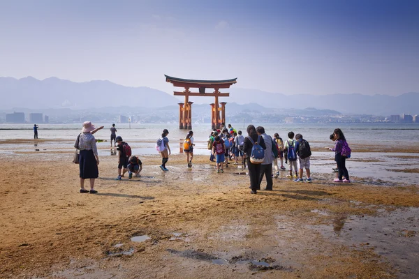 Miyajima, Ιαπωνία - 27 Μαΐου: Τουρίστες βόλτα γύρω από την περίφημη πύλη πλωτή Τορίι από το ιερό της Ιτσουκουσίμα στην Miyajima κατά την άμπωτη εμφανιστεί στο Μαΐου 27,2016 στην Miyajima, Ιαπωνία — Φωτογραφία Αρχείου