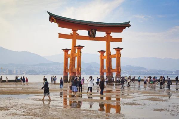 MIYAJIMA, JAPÓN - 27 DE MAYO: Los turistas caminan alrededor de la famosa puerta torii flotante del Santuario de Itsukushima en Miyajima durante la marea baja mostrada el 27 de mayo de 2016 en Miyajima, Japón — Foto de Stock