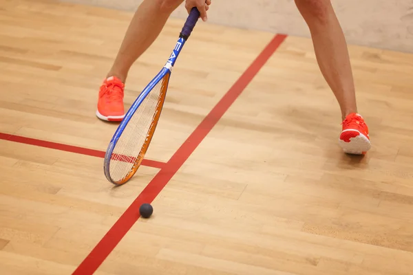 A young female squash player hiting a ball in a squash court — Stock Photo, Image