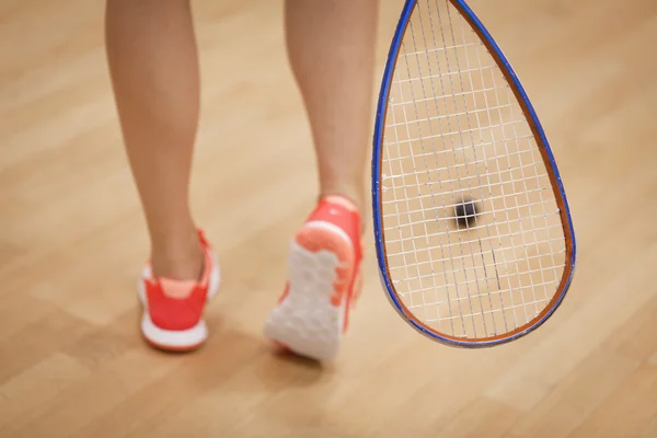 Uma jovem jogadora de squash batendo uma bola em uma quadra de squash — Fotografia de Stock