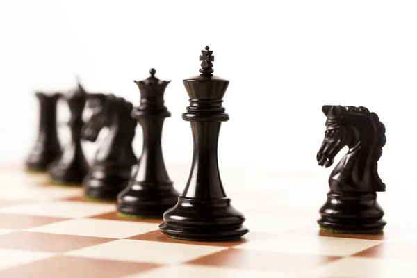 Black chess pieces on a chessboard standing in perspective