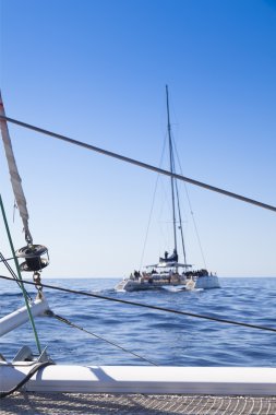 katamaran yelkenli. Sakin mavi okyanus ve Bulutsuz mavi gökyüzü arka planda vardır