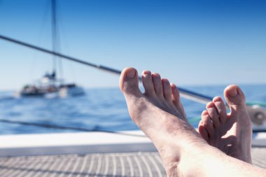 Ayaklarını propped ve çarpı işareti ile bir katamaran yelkenli trambolin üzerinde uzanmanız adam.