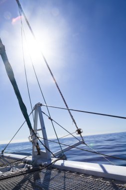 katamaran yelkenli. Sakin mavi okyanus ve Bulutsuz mavi gökyüzü arka planda vardır