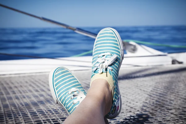 Woman relaxing on a catamaran sailboat trampoline with her feet crossed — Stock Photo, Image