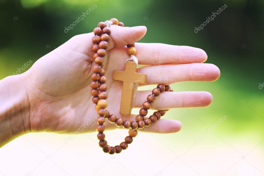 Christian prayer beads in the hand of woman