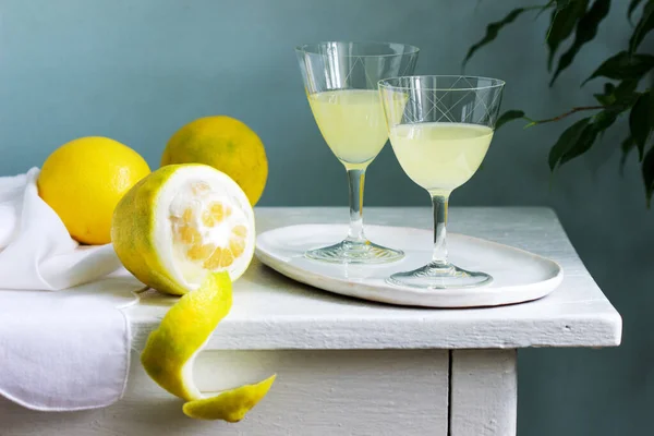 Italienischer Likör Limoncello in Kristallgläsern und reifen Zitronen auf einem Holztisch. — Stockfoto
