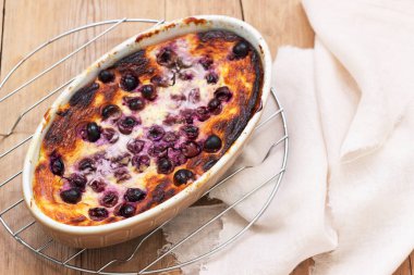 Ahşap bir yüzey üzerinde seramik formda üzümlü kaymak güveci..