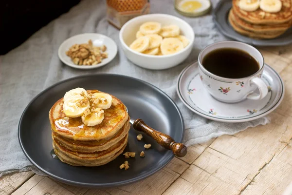 Pancakes with banana, nuts and honey, served with tea. Rustic style. — Stock Photo, Image