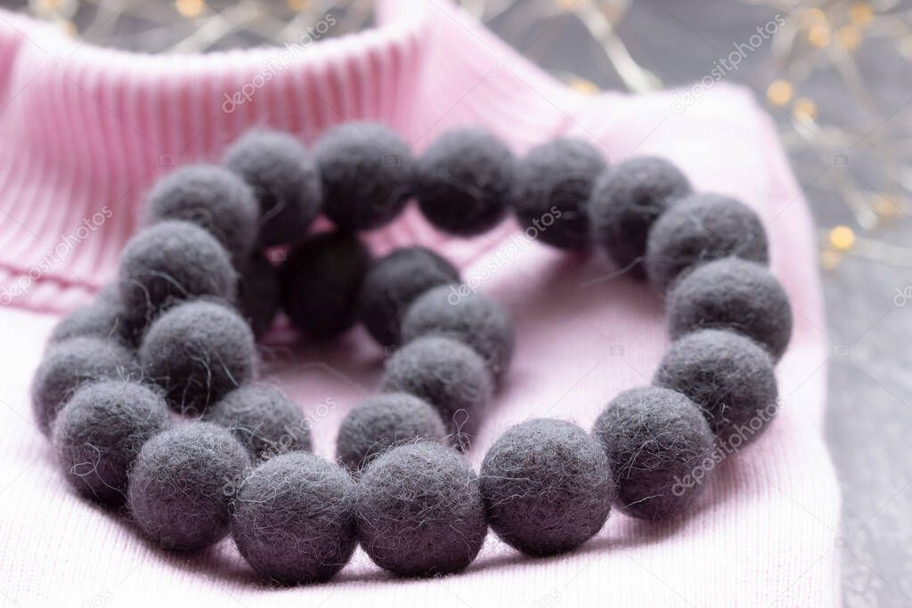 Handmade wool necklace on the background of clothes.
